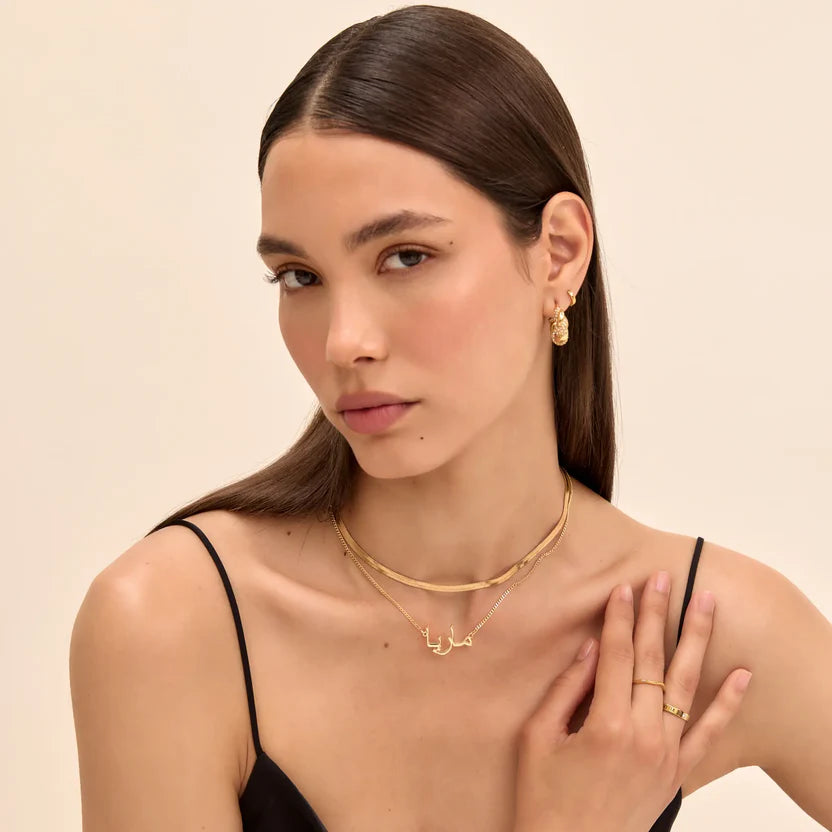 Elegante arabische Namenskette aus Gold am Hals eines Modells