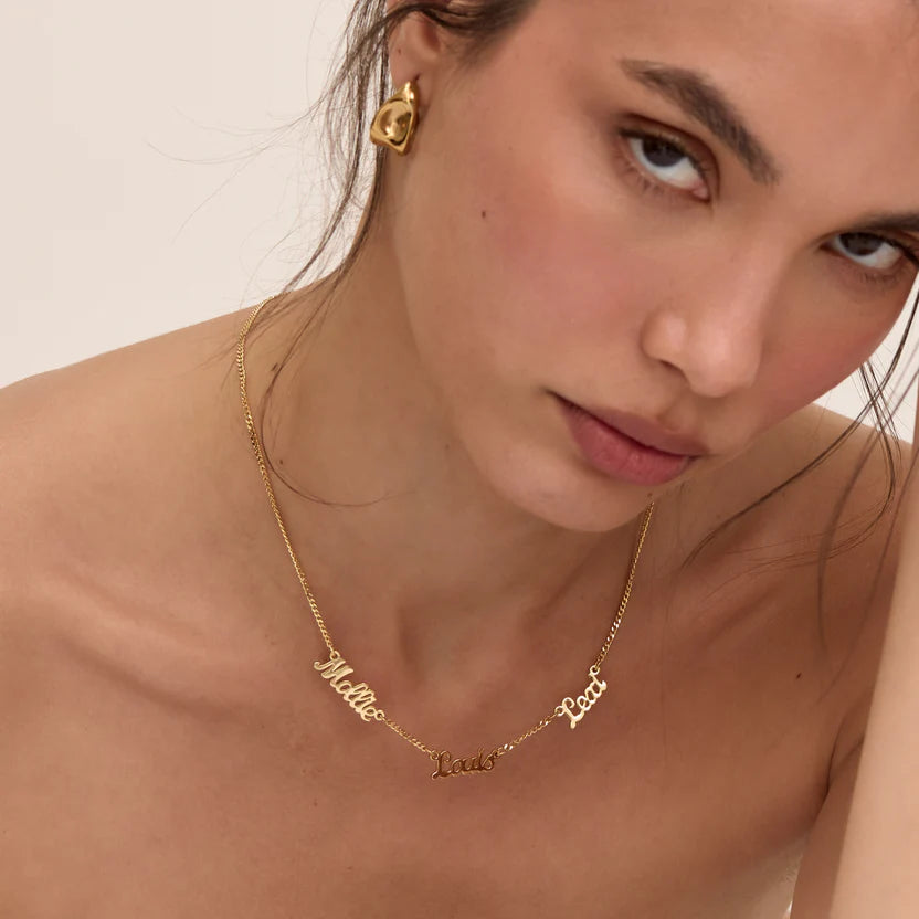 Nahaufnahme der goldenen Namenskette mit mehreren Namen am Hals eines Modells